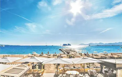a beach with chairs and umbrellas and the ocean at 1 Bedroom Beautiful Apartment In Cannes in Cannes