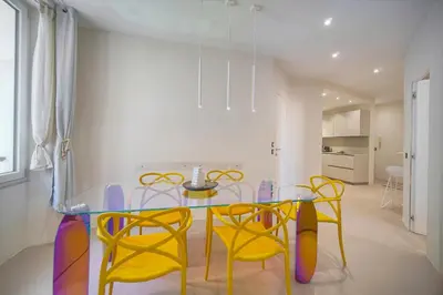a dining room with a glass table and yellow chairs at Moderne 2 chambres, CARRE D'OR- COEUR DE CANNES A2B194 in Cannes