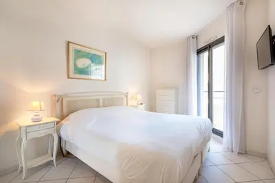a white bedroom with a large bed and a window at Agence des Résidences - Plein centre de Cannes in Cannes