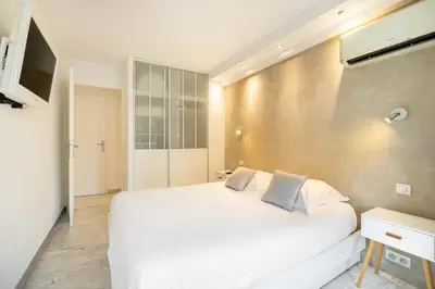 a bedroom with a large white bed and a television at Agence des Résidences - Plein centre de Cannes in Cannes