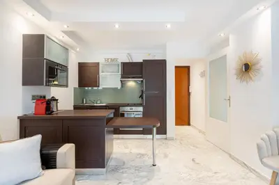 a kitchen with brown cabinets and a table at Agence des Résidences - Plein centre de Cannes in Cannes