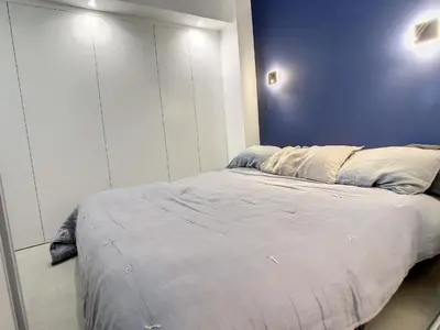 a bedroom with a bed with a blue wall at Penthhouse 1 & 2 bedroom apartment 2 mins from the Croisette 335 in Cannes