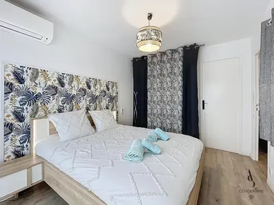 a bedroom with a large bed with blue towels on it at Le Brasilia - 4 pers - 10 min Palais - Climatisé - Centre in Cannes