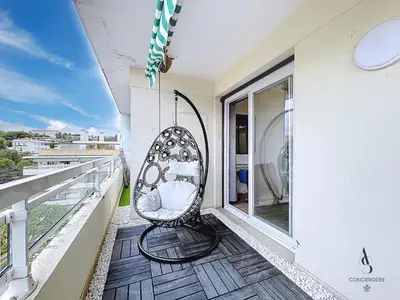 a wicker chair on the balcony of a building at Le Brasilia - 4 pers - 10 min Palais - Climatisé - Centre in Cannes
