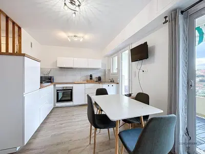 a kitchen with a table and chairs and a kitchen with white cabinets at Le Brasilia - 4 pers - 10 min Palais - Climatisé - Centre in Cannes