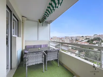 a balcony with two wicker chairs and a view of a city at Le Brasilia - 4 pers - 10 min Palais - Climatisé - Centre in Cannes