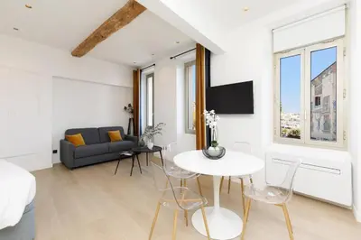 a white living room with a table and a couch at Appartement 33 m2 comme une junior suite - vue Port et Palais des festivals in Cannes