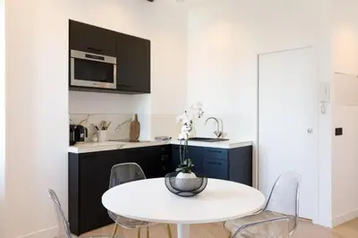 a white kitchen with a white table and chairs at Appartement 33 m2 comme une junior suite - vue Port et Palais des festivals in Cannes