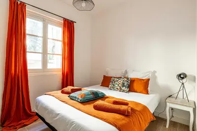 a bedroom with a bed with orange curtains and a window at Résidence Palais des Festivals - Cannes centre in Cannes