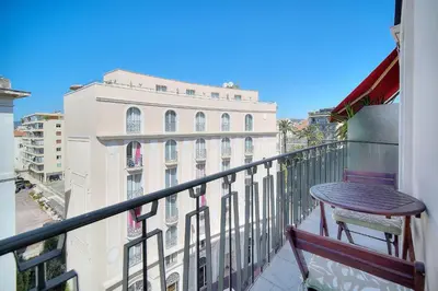 a balcony with a wooden chair and a building at REF 1477 - Apartment for rent in Cannes