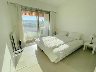 a white bedroom with a bed and a large window at PR Croisette, by Welcome to Cannes in Cannes