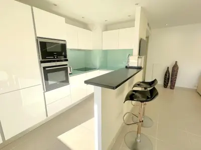 a white kitchen with a black counter and a stool at PR Croisette, by Welcome to Cannes in Cannes