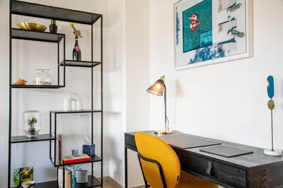 a desk with a yellow chair next to a wall with shelves at Palais Azur in Cannes