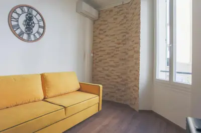a living room with a couch and a clock on the wall at Studio Mimosa - Welkeys in Cannes