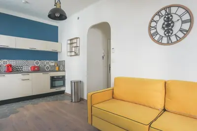 a living room with a couch and a clock on the wall at Studio Mimosa - Welkeys in Cannes