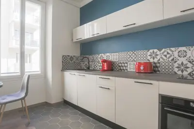a kitchen with white cabinets and a blue wall at Studio Mimosa - Welkeys in Cannes