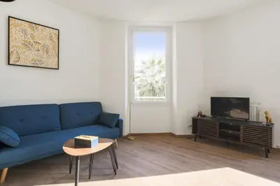 a living room with a blue couch and a tv at Appartement Palme d'Or - Welkeys in Cannes