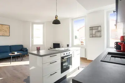 a kitchen with white cabinets and a blue couch at Appartement Palme d'Or - Welkeys in Cannes