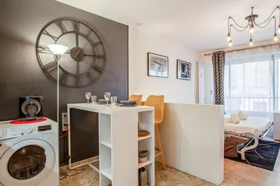 a living room with a washing machine and a clock at Studio Merle - Welkeys in Cannes