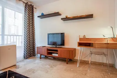 a living room with a television on a wooden entertainment center at Studio Merle - Welkeys in Cannes