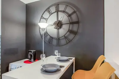 a dining room with a clock on the wall at Studio Merle - Welkeys in Cannes