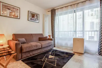 a living room with a brown couch and a large window at Studio Merle - Welkeys in Cannes