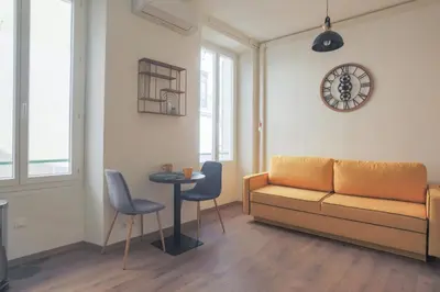 a living room with a couch and a table and a clock at Studio Soleil - Welkeys in Cannes