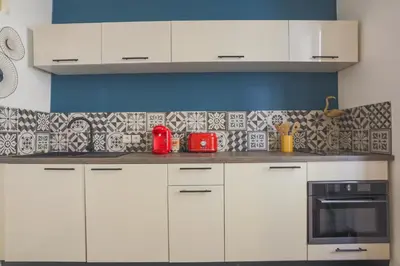 a kitchen with white cabinets and a red appliance at Studio Soleil - Welkeys in Cannes