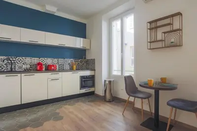 a kitchen with white cabinets and a table with chairs at Studio Soleil - Welkeys in Cannes