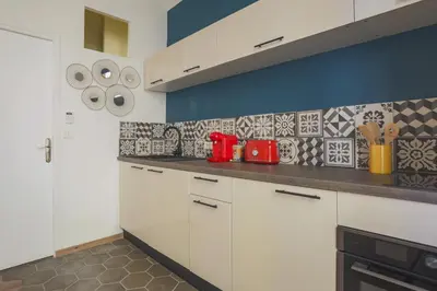 a kitchen with white cabinets and red appliances at Studio Soleil - Welkeys in Cannes