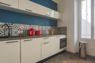 a kitchen with white cabinets and a blue wall at Studio Soleil - Welkeys in Cannes