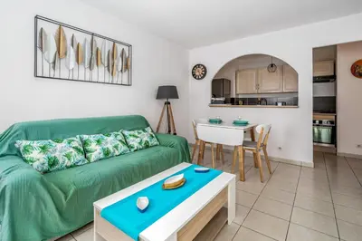 a living room with a green couch and a table at Appartement Libériade - Welkeys in Cannes