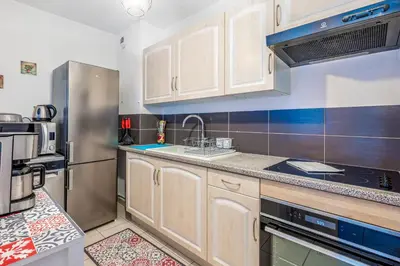 a kitchen with white cabinets and a stainless steel refrigerator at Appartement Libériade - Welkeys in Cannes