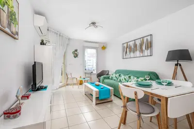 a living room with a green couch and a table at Appartement Libériade - Welkeys in Cannes