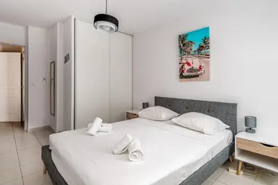 a bedroom with a bed with white sheets and pillows at Appartement Libériade - Welkeys in Cannes