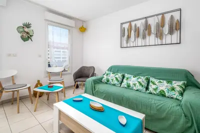 a living room with a green couch and a table at Appartement Libériade - Welkeys in Cannes