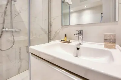 a white bathroom with a sink and a shower at Studio Lys - Welkeys in Cannes