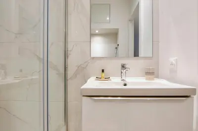 a white bathroom with a sink and a shower at Studio Lys - Welkeys in Cannes