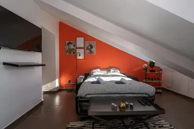 a bedroom with an orange accent wall and a bed at Le Laeti - 600m plage - Verrière Côte d'Azur in Cannes
