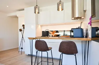 a kitchen with a counter and two stools in a kitchen at Le Flore - Appartement neuf - Cannes Center in Cannes