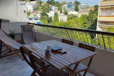 a wooden table on a balcony with a book on it at Appartement proche croisette avec parking et climatisation in Cannes