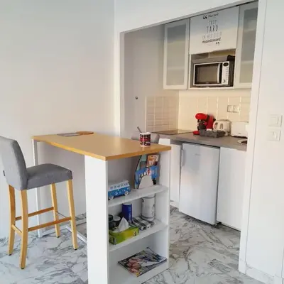 a kitchen with a table and a chair and a counter at Appartement proche croisette avec parking et climatisation in Cannes