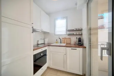 a white kitchen with white cabinets and a window at Beau 2 chambres TERRASSE, COEUR DU SUQUET-entre Port et Plages A2B238 in Cannes