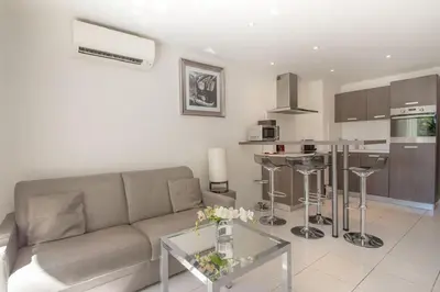 a living room with a couch and a kitchen at Croisette: 2BDR Apartment in Cannes