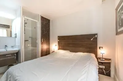 a bedroom with a large white bed and a bathroom at Croisette: 2BDR Apartment in Cannes