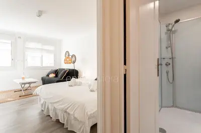 a white bedroom with a bed and a glass shower at 
