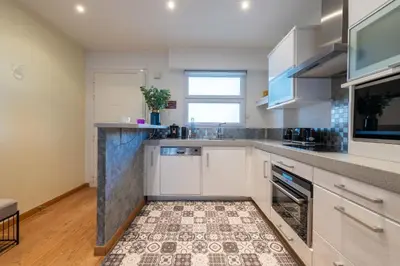 a kitchen with white cabinets and a tile floor at 2-Bedroom Apartment with Terrace and Side Sea View in Cannes