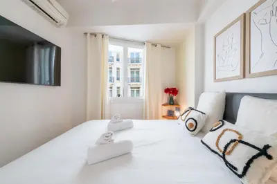 a white bedroom with a large white bed with a window at 2-Bedroom Apartment with Terrace and Side Sea View in Cannes