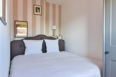 a bed with white sheets and pillows in a room at L'ALIZEE avec jolie terrasse vue sur la ville, charmant studio dans le centre de Cannes in Cannes