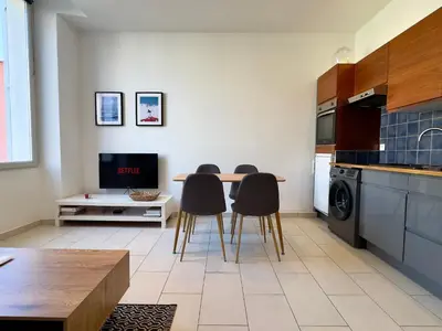a kitchen with a table and chairs and a tv at Andréa By SCLS Locations in Cannes